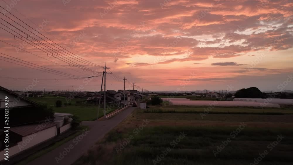 Car drives down narrow country road under dramatic sunset Car drives down narrow country road under dramatic sunset