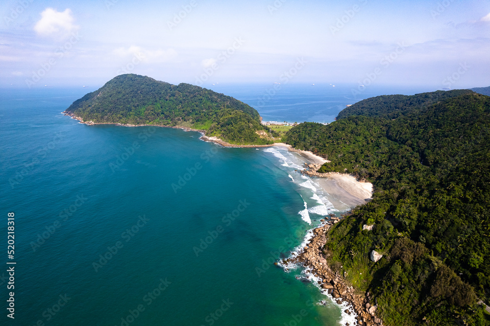Imagem aérea da praia do Tombo, localizada na cidade do Guarujá. Ondas, natureza, montanhas e banhistas.