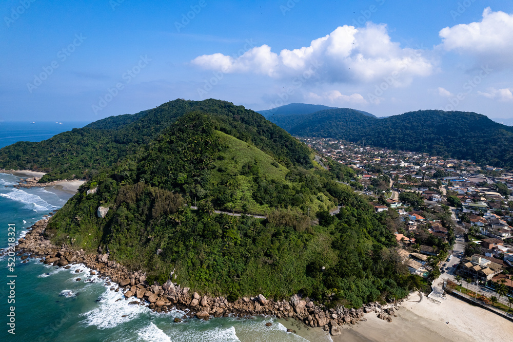 Imagem aérea da praia do Tombo, localizada na cidade do Guarujá. Ondas, natureza, montanhas e banhistas.