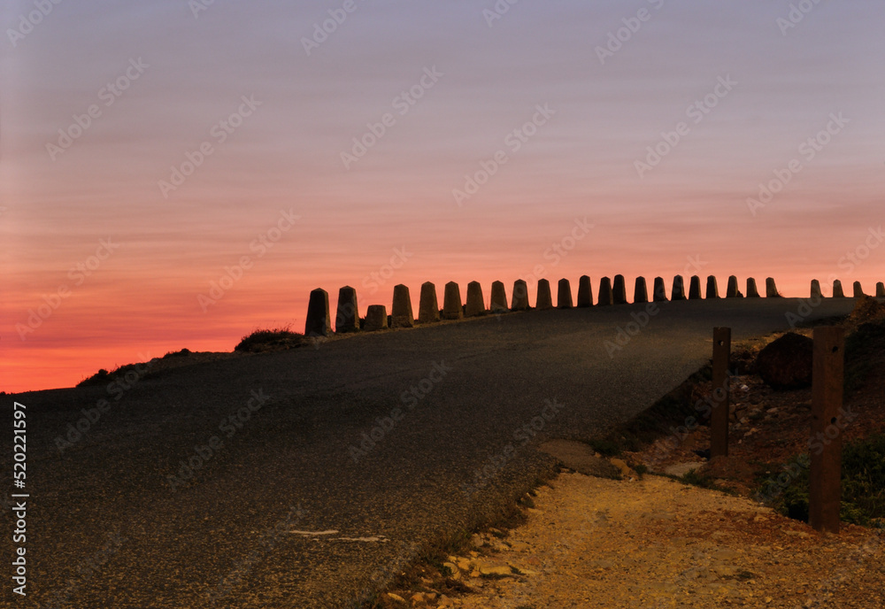 Estrada antiga de montanha com mecos em pedra, nascer do sol no horizonte