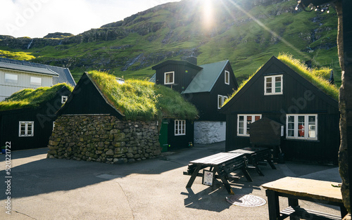 Old stone houses with a grass (turf) roof. Tourist sightseeing in green valley. Village on Faroe Islands. photo