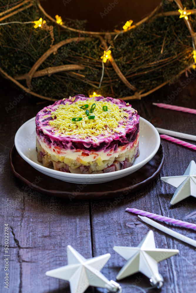 Dressed herring, raditional Soviet festive salad of herring and vegetables in a New Year's decoration.