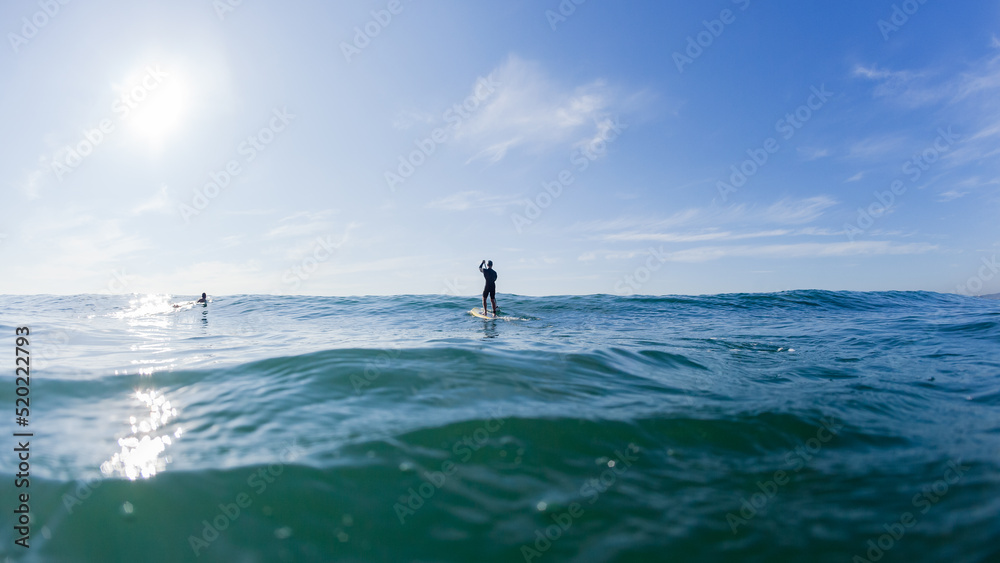 Surfer Paddle Board Ocean Paddling Towards Blue Sky Horizon. Surfer Paddle Board Ocean Paddling Towards Blue Sky Horizon.