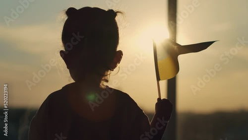 A frightened child stands near the window and waves the Ukrainian flag
