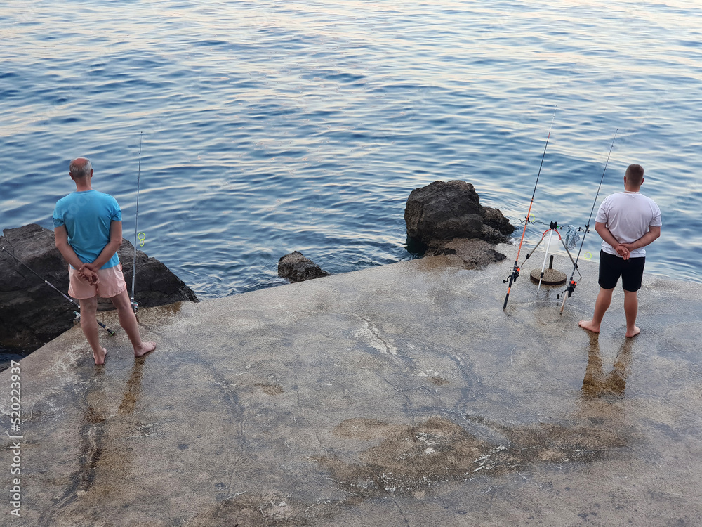 Two fishermen are waiting for the fish to bite Two fishermen are waiting for the fish to bite