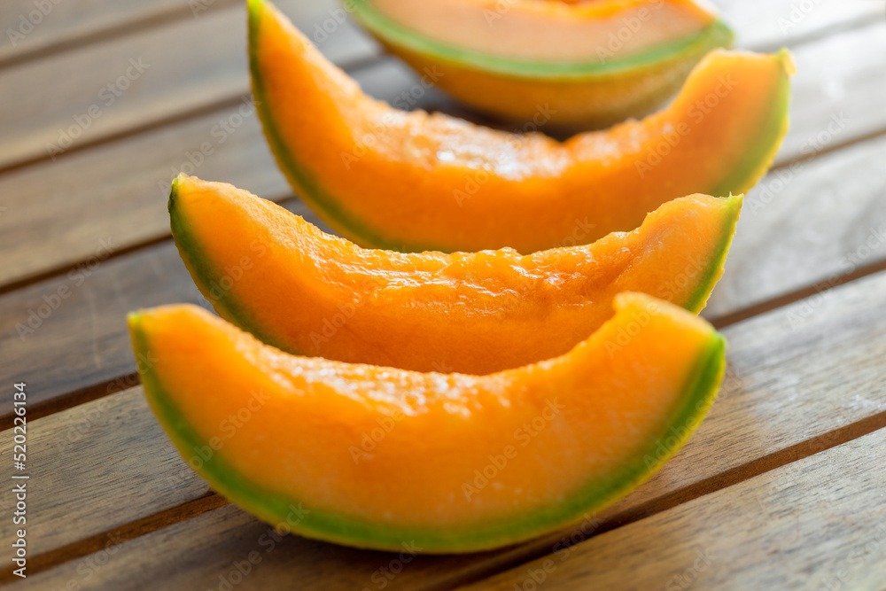 Fresh juicy orange melon slices on wooden table close up