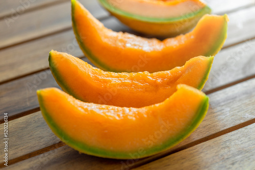 Fresh juicy orange melon slices on wooden table close up