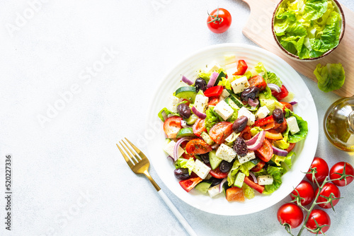Greek salad. Vegetable salad with tomato, cucumber, feta cheese and olive oil. Top view on white stone table.