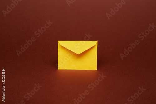Yellow color paper office envelope for greeting or invitation with copy space isolated on the bright solid fond plain dark brown background