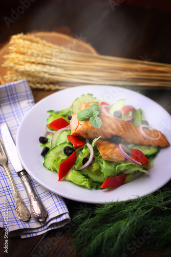 Appetizing salmon fish out of the oven with salad and olives