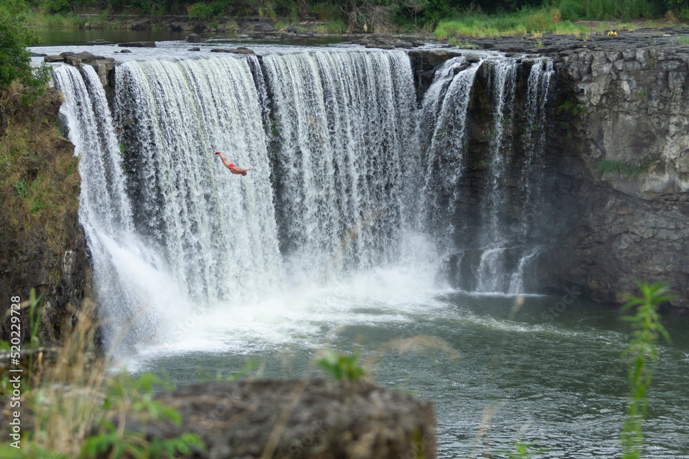 A men is diving from a cliff at Jingbo Lake falls in Heilongjiang, China. Waterfall and Mountain landscape. A men is diving from a cliff at Jingbo Lake falls in Heilongjiang, China. Waterfall and Mountain landscape.