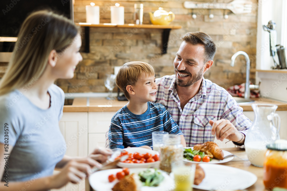 Happy parents enjoying with their small son during breakfast time in the kitchen