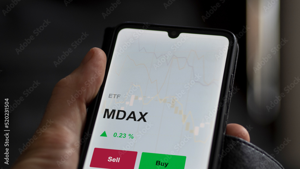 Un investisseur analyse un fonds etf mdax sur un graphique. Un téléphone affiche le cours de l'ETF MDAX
