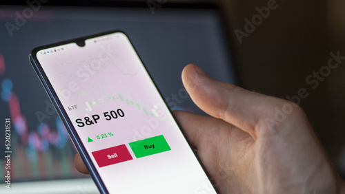 Un investisseur analyse un fonds etf s&p 500 sur un graphique. Un téléphone affiche le cours de l'ETF S&P 500