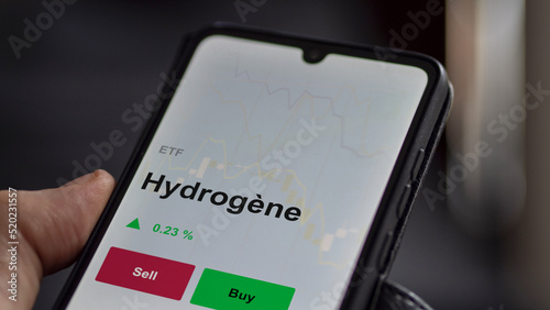 Un investisseur analyse un fonds etf hydrogène sur un graphique. Un téléphone affiche le cours de l'ETF Hydrogène