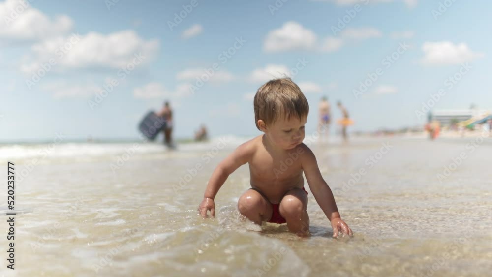Kid collects shells and pebbles in the sea on a sandy bottom under the summer sun on a vacation Kid collects shells and pebbles in the sea on a sandy bottom under the summer sun on a vacation