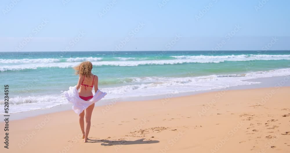 Feminine woman standing on sandy seashore during summer holiday Feminine woman standing on sandy seashore during summer holiday
