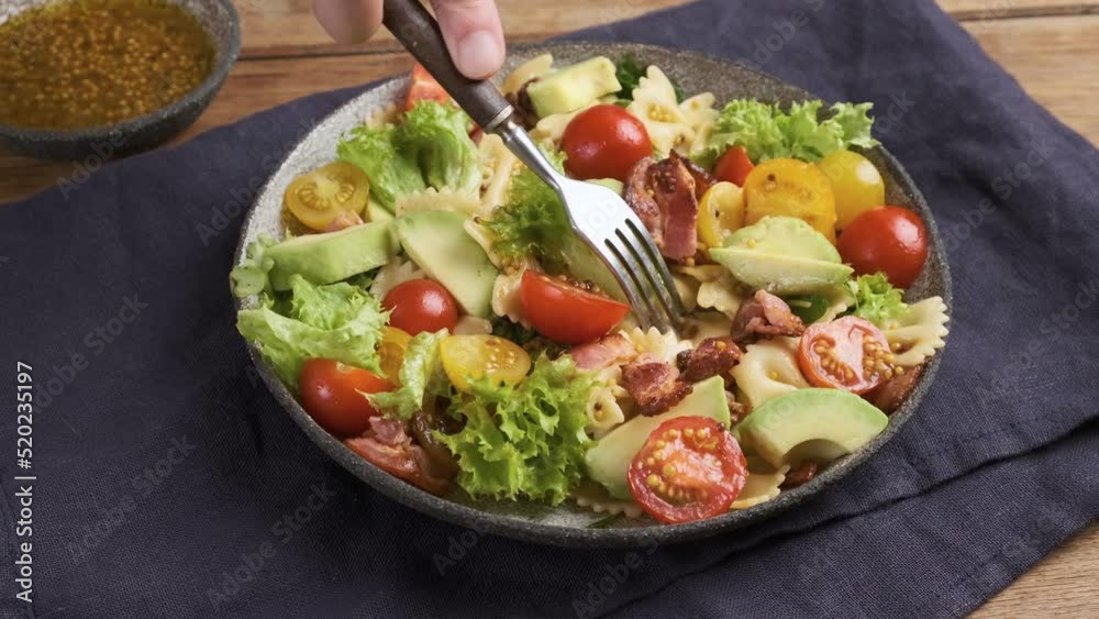 Eating salad with pasta farfalle, tomato, bacon, avocado and mustard with fork. Healthy food. 4k video Eating salad with pasta farfalle, tomato, bacon, avocado and mustard with fork. Healthy food. 4k video