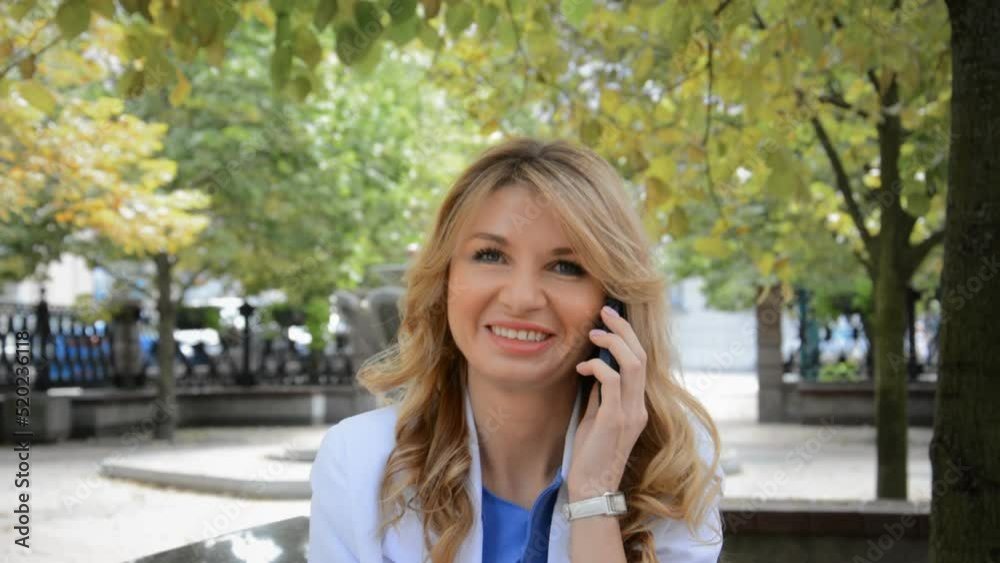 Beautiful business woman blonde portrait talking on the phone in a city park Beautiful business woman blonde portrait talking on the phone in a city park