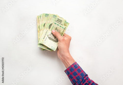 Mano de un hombre joven sosteniendo varios billetes de doscientos pesos mexicanos sobre un fondo blanco  photo