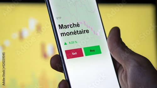 Un investisseur analyse un fonds etf marché monétaire sur un graphique. Un téléphone affiche le cours de l'ETF. Texte en français francais Marché monétaire photo