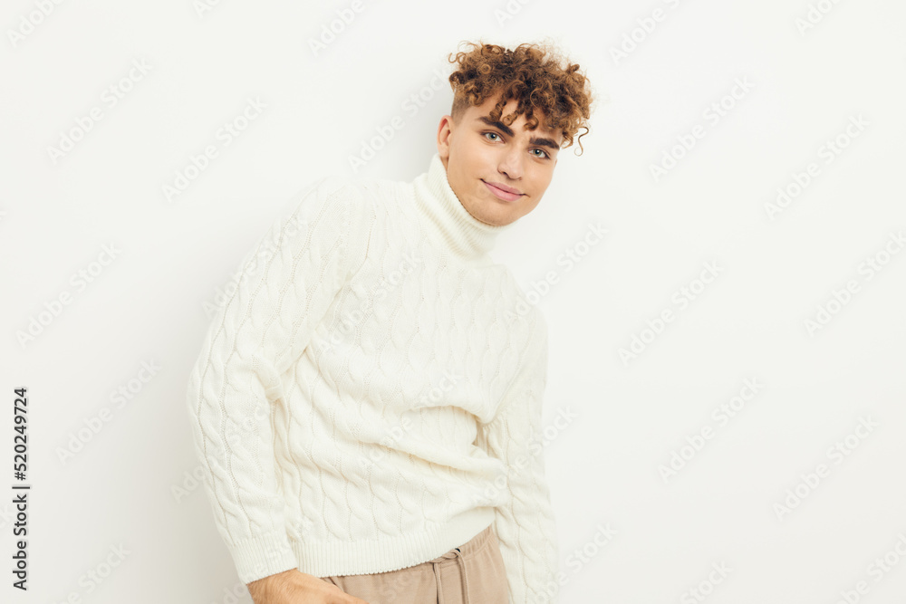 a close horizontal photo of a handsome, attractive man with curly hair standing in a white knitted sweater on a light background posing relaxed a close horizontal photo of a handsome, attractive man with curly hair standing in a white knitted sweater on a light background posing relaxed