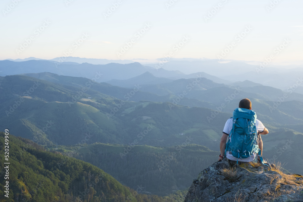 Man sitting on the top contemplating the road traveled.