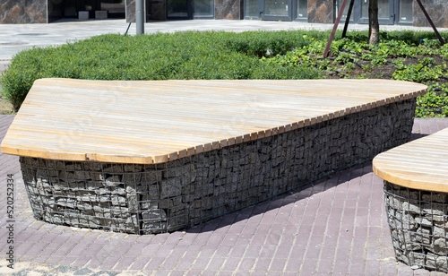 Wooden benches from gabion baskets with stones inside. Wood mounted on gabions. Benches of modern design. There is a recreation area. Detail of a low gabion wall with a wooden top. photo