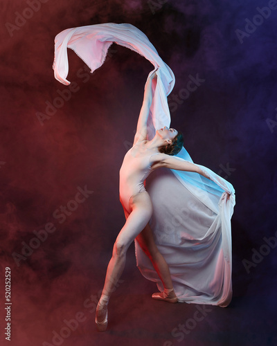 Fototapeta Naklejka Na Ścianę i Meble -  charming ballerina posing with chiffon fabric in a studio in colored smoke
