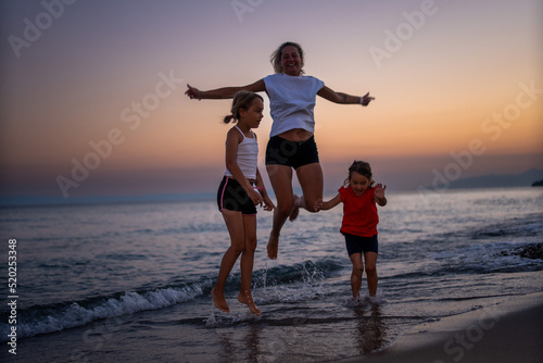 a young mother with two daughters enjoys an evening walk along the seashore. They are on vacation. Vacation concept.