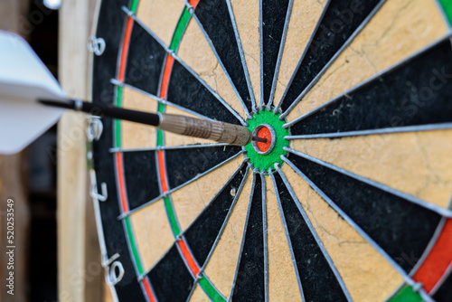a dart stuck in the center of a dartboard on a wooden wall