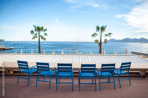 Row of blue chairs in front of the sea in Cannes