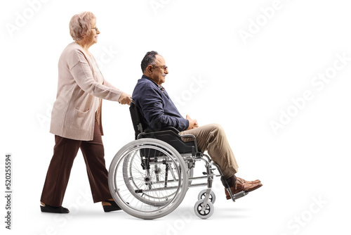 Elderly woman pushing a mature man in a wheelchair © Ljupco Smokovski