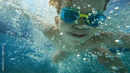 Male kid jumping to blue swimming pool bubbles water happy childhood underwater shot slow motion
