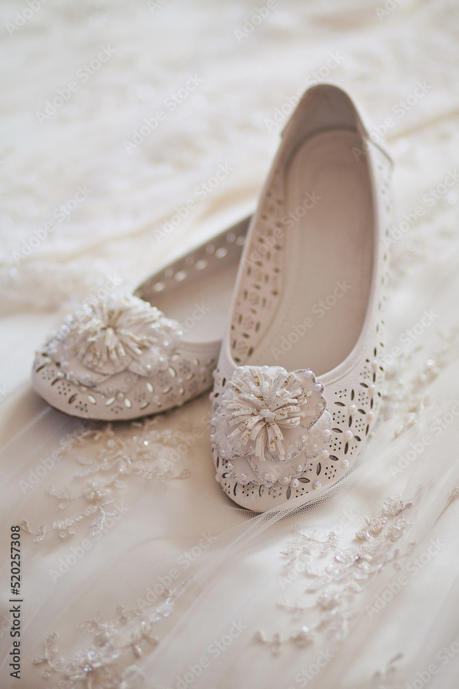 White shoes lie on a wedding dress White shoes lie on a wedding dress