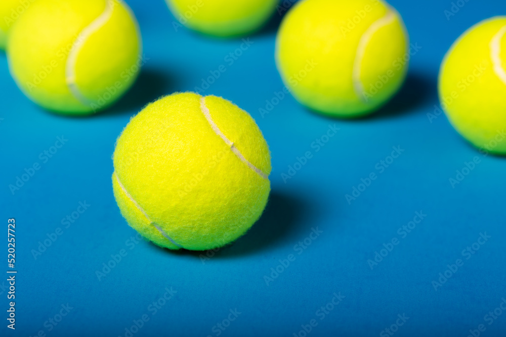 Macro, close-up of tennis ball with additional tennis balls blurred in background.
