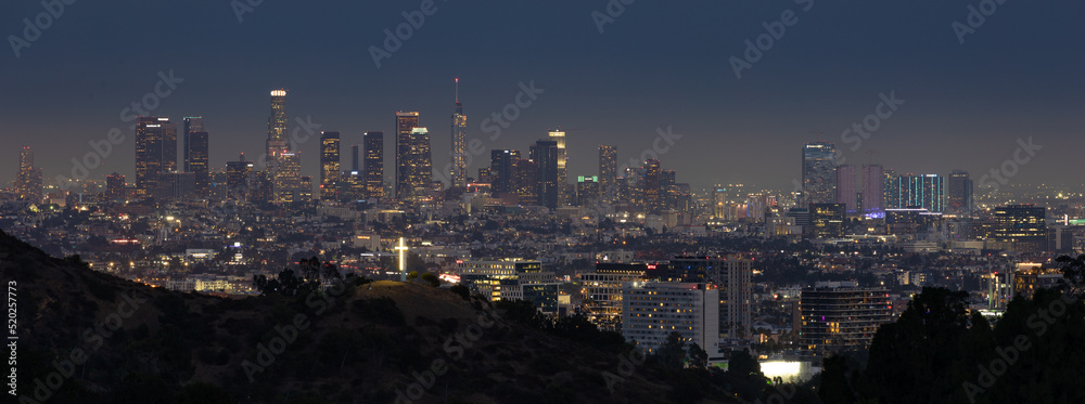 Skyline of Los Angeles at blue hour with a lighted cross in the foreground