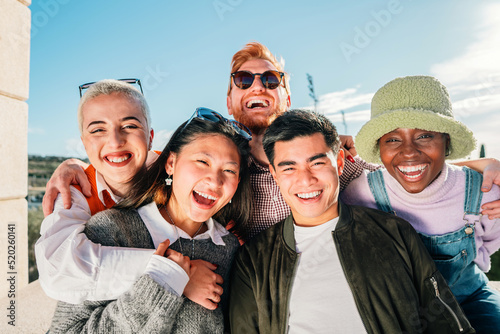 Five multi-ethnic friends posing for a photo smiling and having fun outdoor.