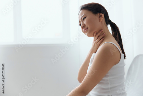 Tickling Cough. Side view of suffering crying tanned beautiful young Asian woman touch neck sore throat at home interior living room. Injuries Poor health Illness concept. Cool offer Banner