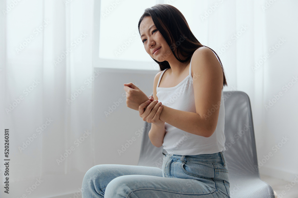 Tormented suffering from dislocation tanned beautiful young Asian woman hurting holding painful wrist at home interior living room. Injuries Poor health Illness concept. Cool offer Banner Tormented suffering from dislocation tanned beautiful young Asian woman hurting holding painful wrist at home interior living room. Injuries Poor health Illness concept. Cool offer Banner