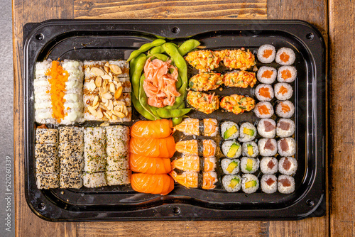  Sushi black plate on wood table, top view.