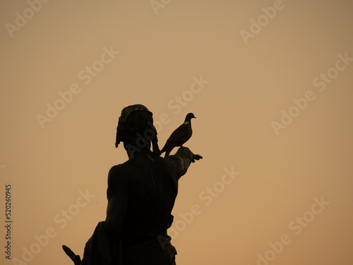 bronze sculpture at sunset in backlight with a dove perched. Concept of peace photo