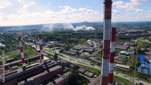 Panoramic top view of the industrial landscape of technological pipes and plant settings. Footage. Industrial production on background of city and distant forest on horizon. Concept of industry in