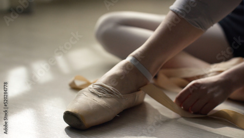 ballet dancer tie up her pointes. Ballet dancer tying ballet shoes before training © Media Whale Stock