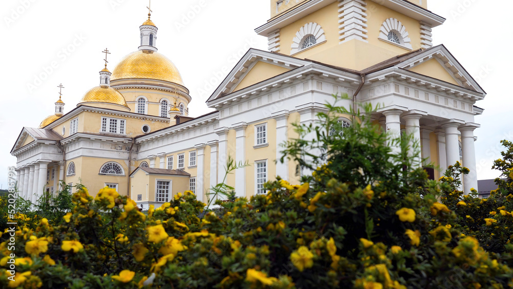 Beautiful architectural facade of the Christian Church with Golden domes. Stock footage. White walls of Church with Golden domes on background of cloudy sky