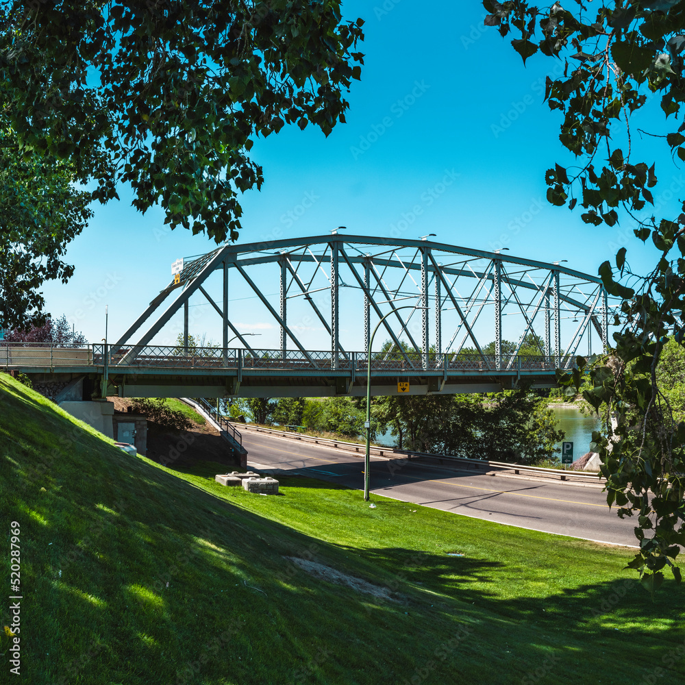 Fototapeta premium Finlay Bridge over South Saskatchewan River and the green hill of Veteran's Memorial Park in Medicine Hat city in Alberta, Canada