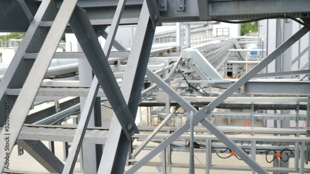 Exterior of large modern factory. Metal structures at factory. Modern structural steel structure of new industrial building. Construction of modern factory or warehouse. Crane lowers roofing. Chemical