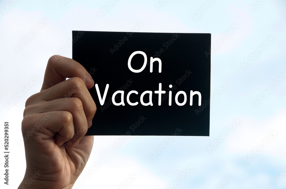 Hand holding black notepad with text - On vacation. Vacation concept