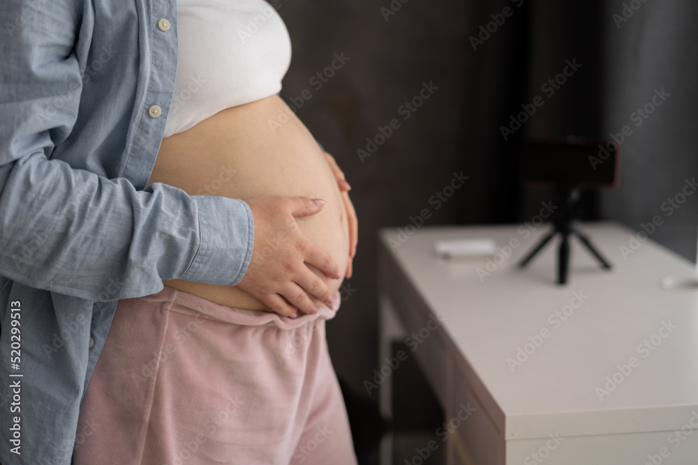 pregnant woman stands and touches her big belly. Emotionally loving pregnancy is 32 weeks. Waiting for a child. Love, happiness and security. Close-up.