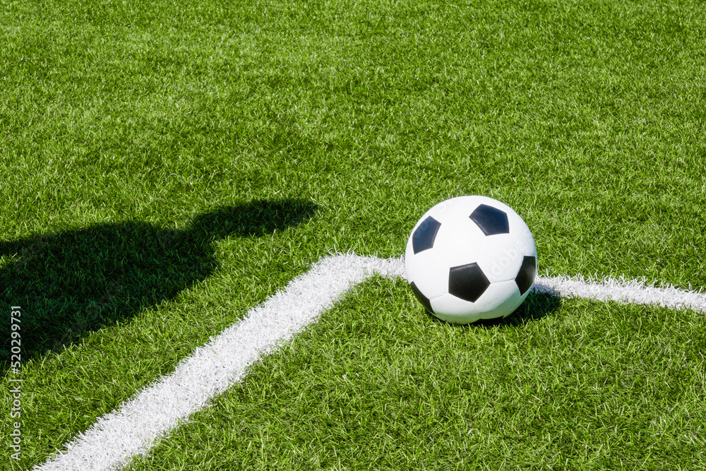 Soccer football sport background. Soccer ball and shadow of player on artificial turf soccer field in sunny day outdoors Soccer football sport background. Soccer ball and shadow of player on artificial turf soccer field in sunny day outdoors